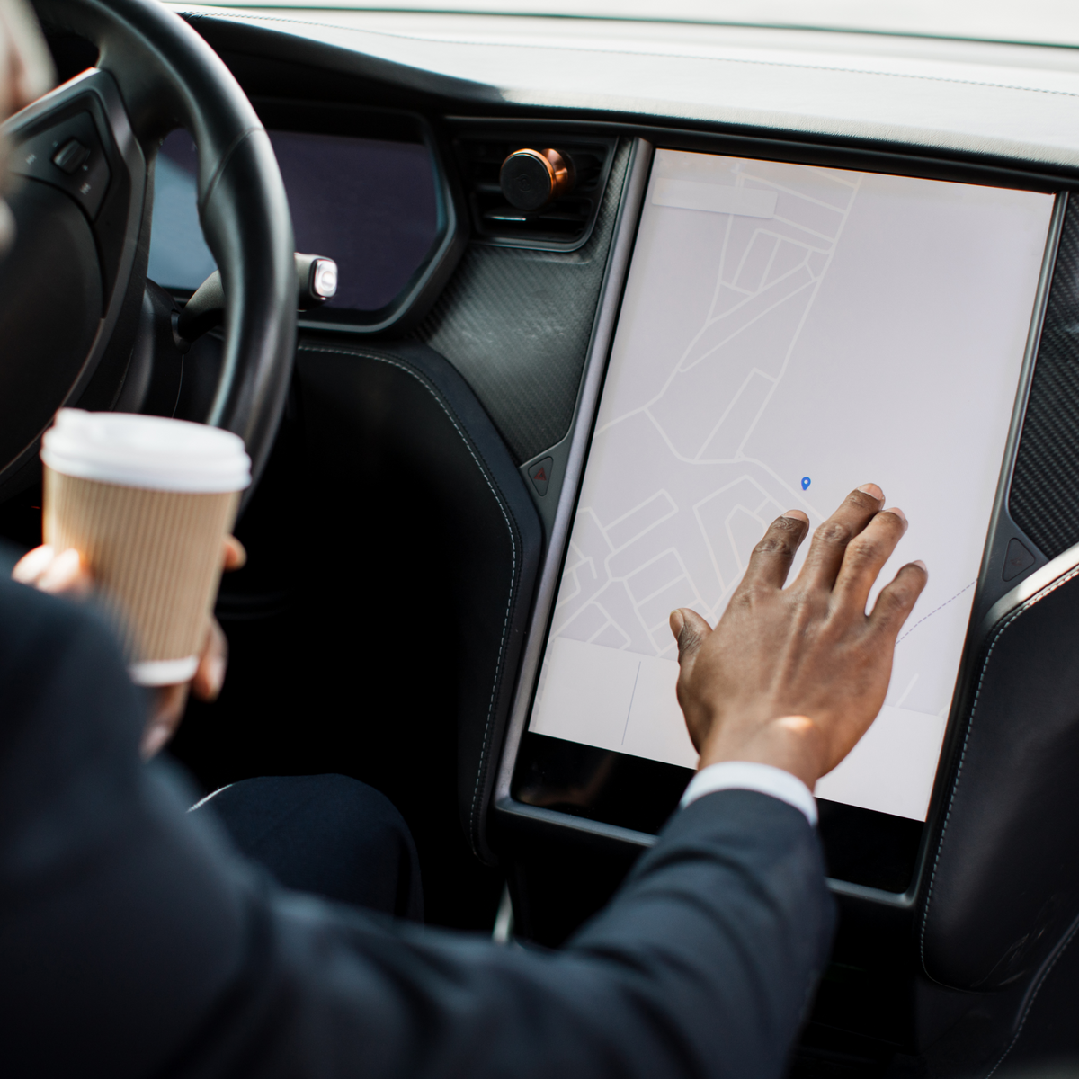 Person driving a car interacting with a touchscreen on their dashboard