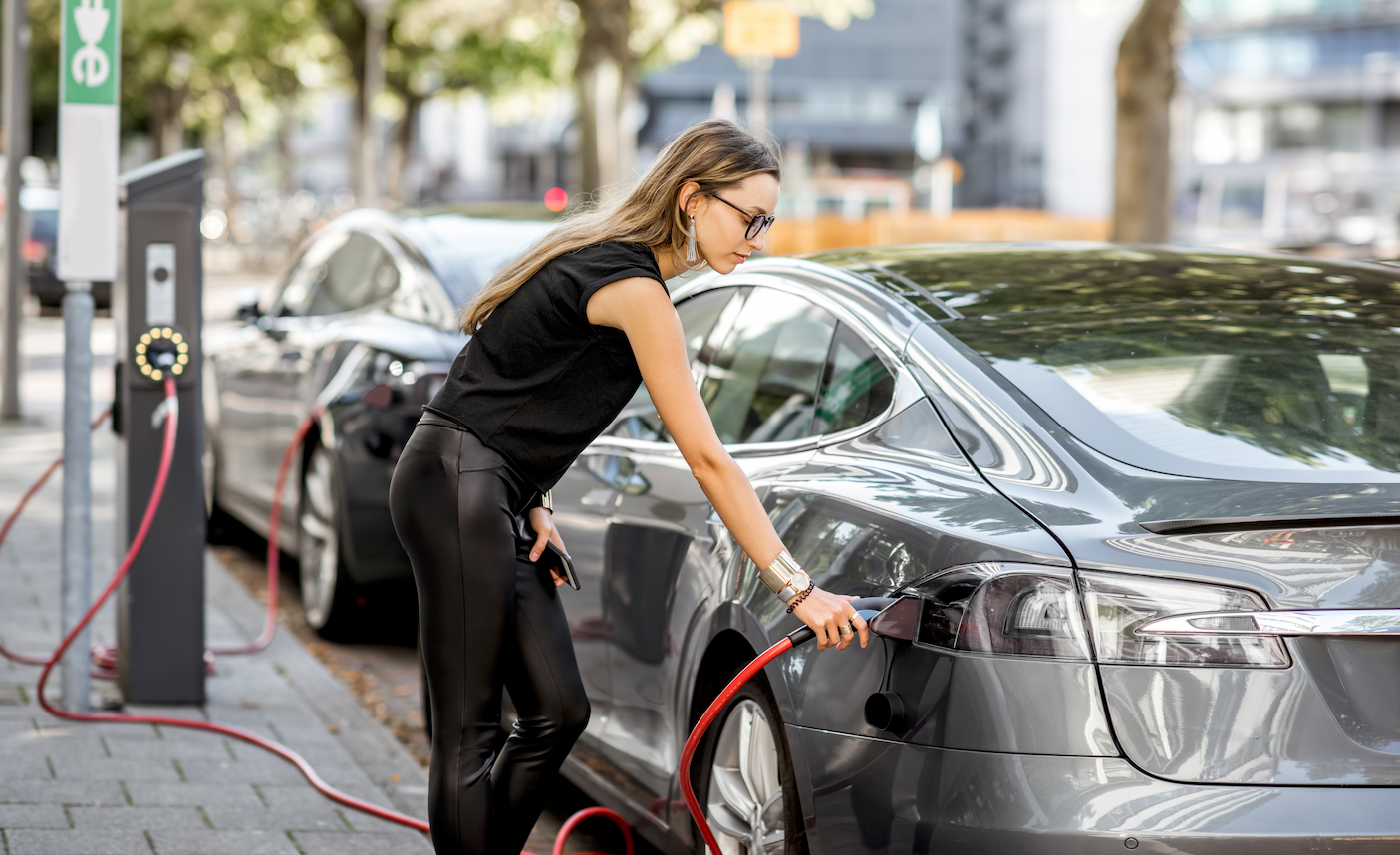 A woman plugging a charger into an electric vehicle