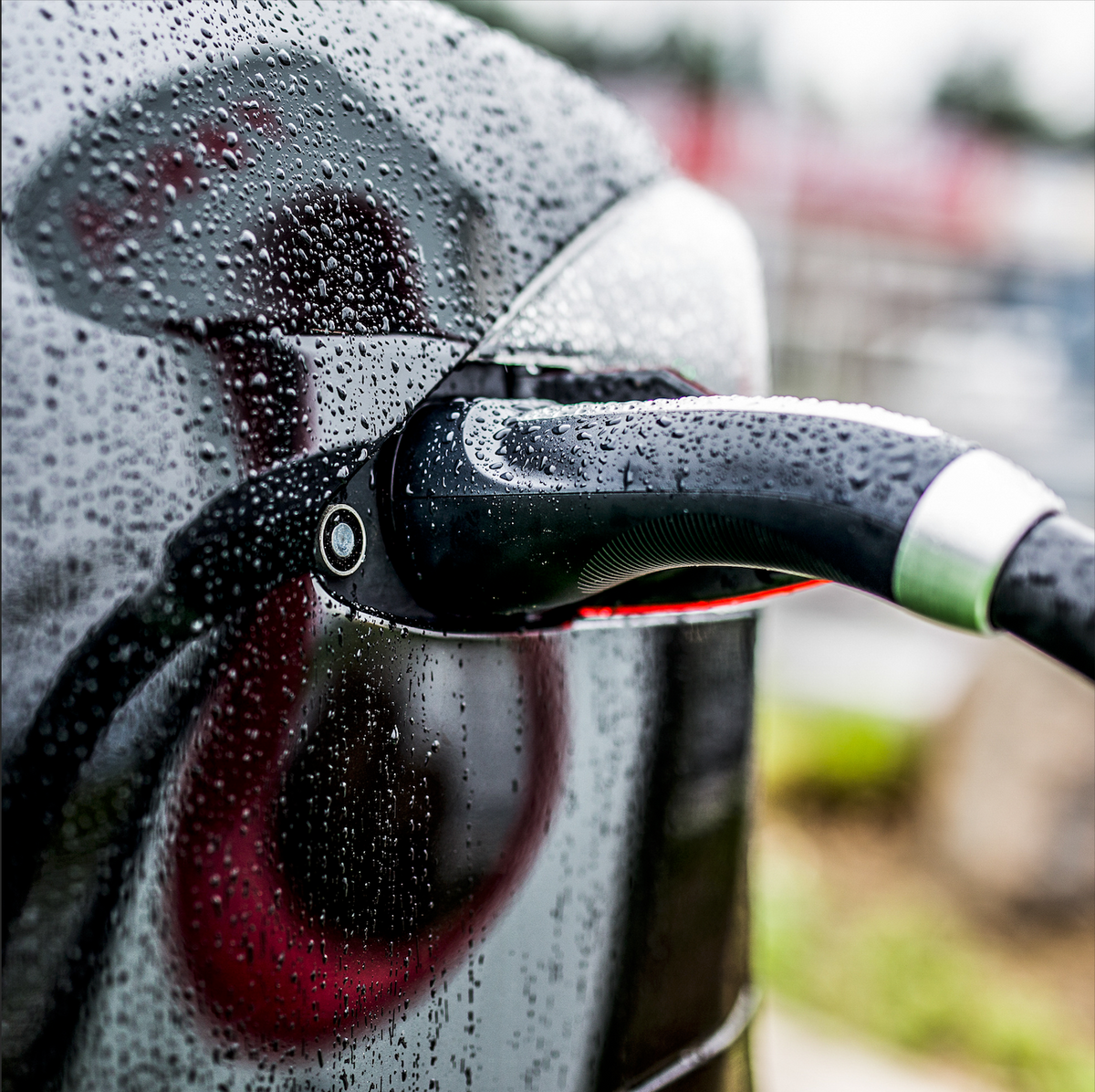 Electric vehicle charger plugged into a vehicle, covered in drops of water